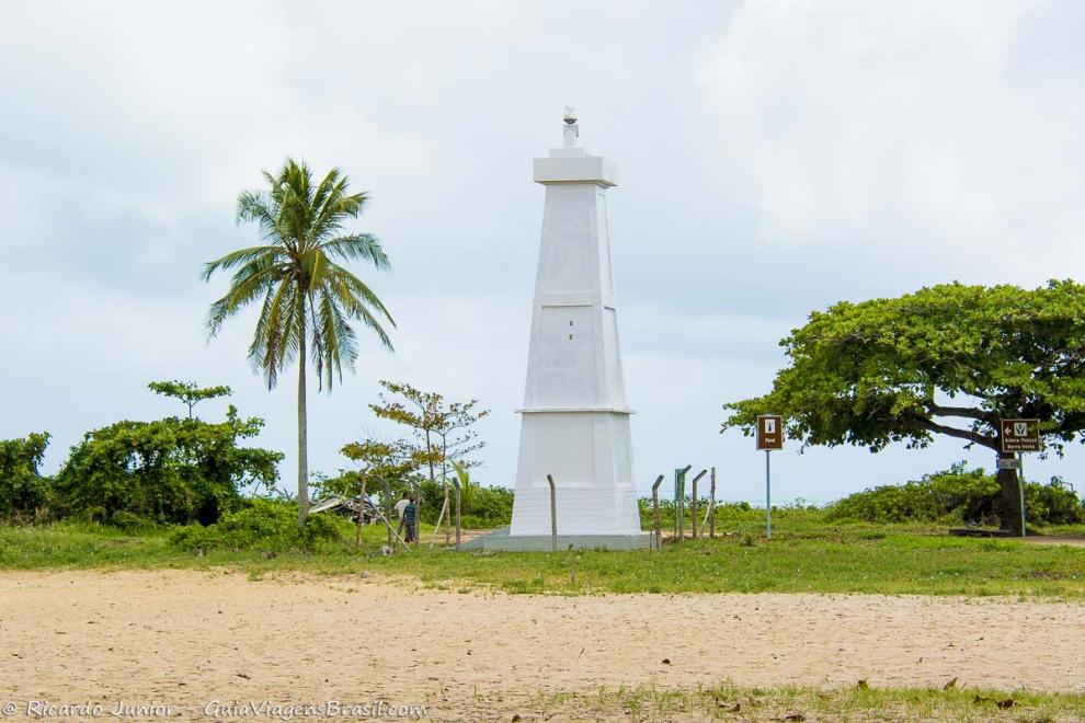 Imagem de farol no meio de duas árvores na Praia Corumbau.